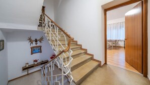 Un escalier avec des rampes en bois et une balustrade blanche, menant à une pièce dotée d’un plancher en bois et d’une porte.