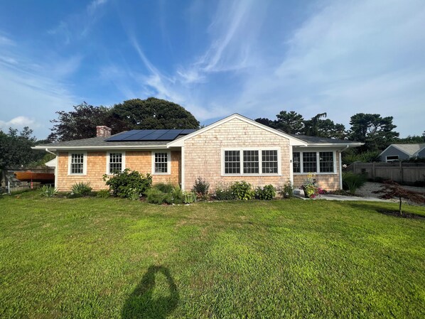 A two-story house with a brick facade, large windows, and a solar panel on the roof. - Cape Cod Tranquility in Falmouth Village (Falmouth)