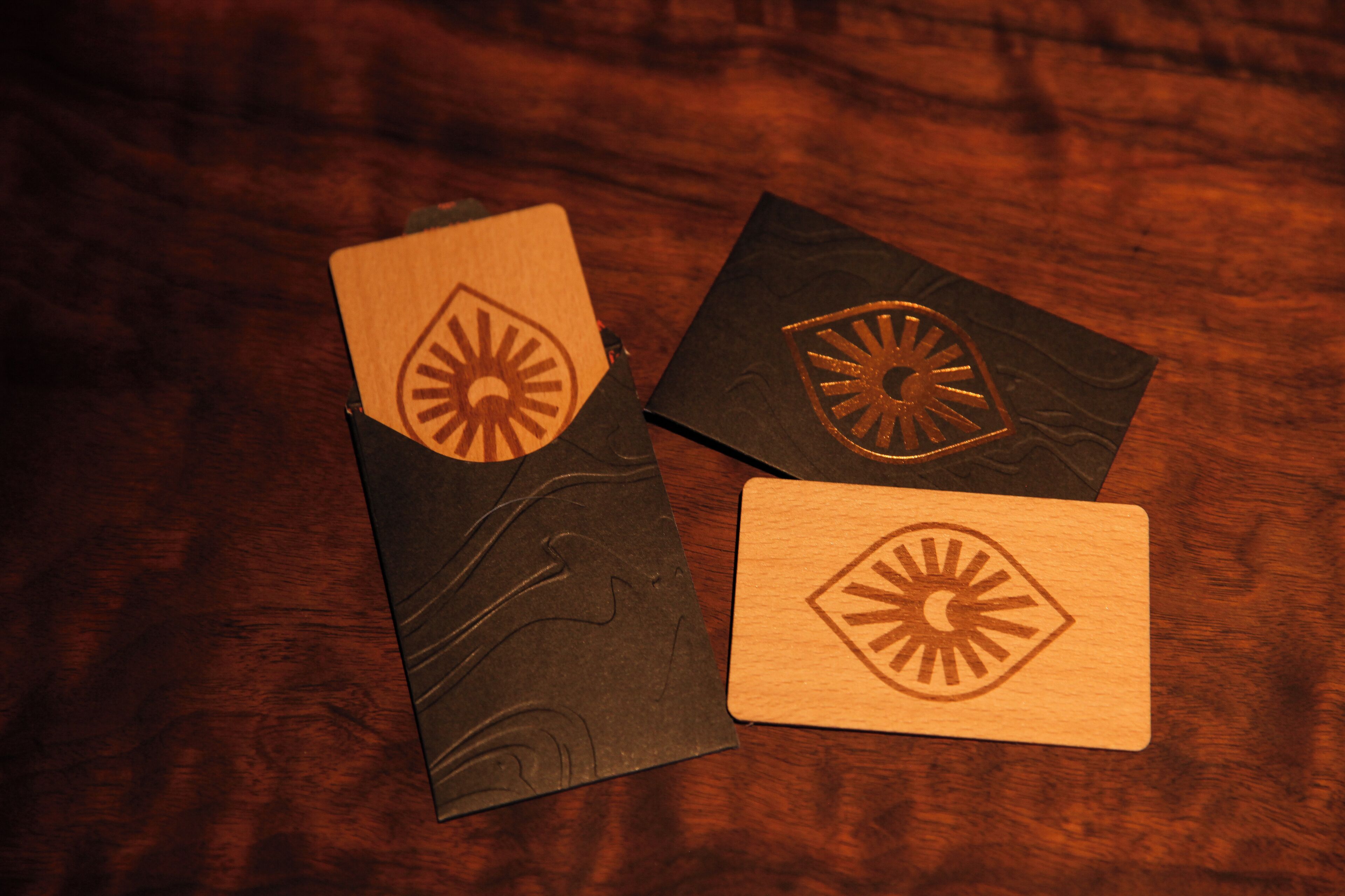 Three wooden cards with sun and eye designs on a wooden surface.
