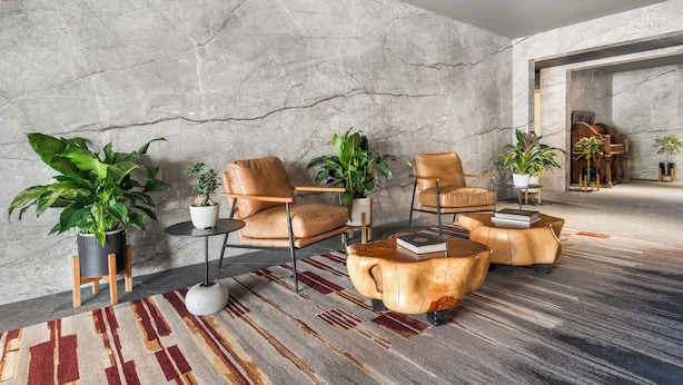 A modern living room with a marble wall, leather armchairs, a wooden coffee table, and potted plants. - Wolfe's Hotel Moab (Moab)