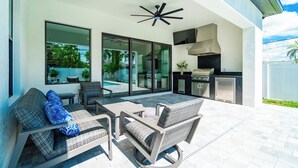 An outdoor patio with wicker furniture, a ceiling fan, and a built-in grill.
