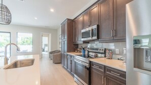 A modern kitchen with stainless steel appliances, wooden cabinets, and a large window.