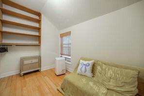 A room with a wooden wardrobe, a white radiator, a beige sofa with a decorative pillow, and a window with blinds. - Lakefront West Sand Lake Home w/ Beach Access! (West Sand Lake)