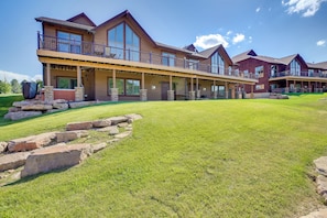 A large, multi-story building with a covered patio area and a well-maintained lawn. - Hot Tub + Golf Course Views: Luxe Sturgis Home! (Sturgis)