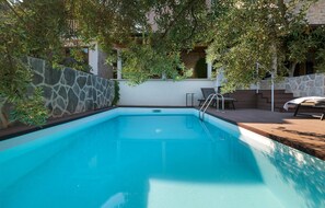 A swimming pool with stone walls, a wooden deck, and outdoor furniture. - Villa Bea (Dvor Pitve Villa B) (Jelsa)