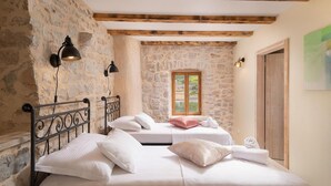 A bedroom with two beds, stone walls, wooden beams, and a window with a view. - Villa Bea (Dvor Pitve Villa B) (Jelsa)