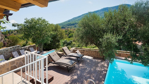 A wooden deck with a pool, lounge chairs, and a stone wall. - Villa Bea (Dvor Pitve Villa B) (Jelsa)
