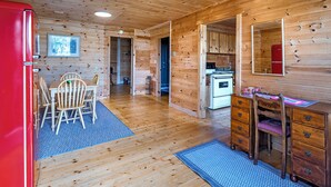 Ein Holzblockhaus im Inneren mit Essbereich, Küche und einem roten Kühlschrank.