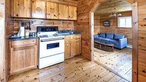 Ein Holzblockhaus-Interieur mit Küche, Essbereich und einer Couch.