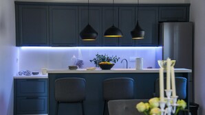 A modern kitchen with dark blue cabinets, a central island with a sink, and pendant lights.