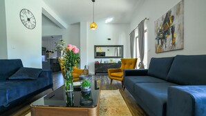 A modern living room with two sofas, a coffee table, a vase with flowers, and a painting on the wall.