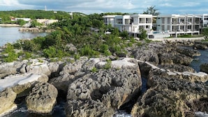 Um hotel costeiro com arquitetura moderna, litoral rochoso e vegetação exuberante.