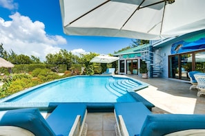 A swimming pool with lounge chairs, a covered patio area, and a staircase leading to an upper level. - Stunning 3BR Lagoon Home with Sunset Rooftop Deck (Placencia)