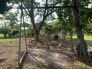 Relax in a serene natural setting surrounded by lush greenery and a rustic structure.