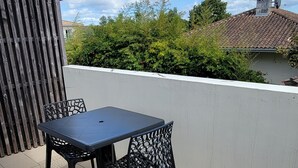 Een terras met een tafel en stoelen, een betegelde vloer, en uitzicht op een gebouw en bomen.
