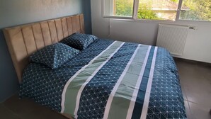 Een slaapkamer met een bed, een raam en een radiator.