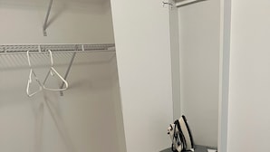 Habitación con estación de planchado integrada, perchero y toma de corriente en la pared.
