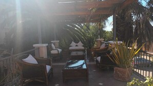 Un patio al aire libre con mobiliario de mimbre, plantas en macetas y una estructura de p érgola.