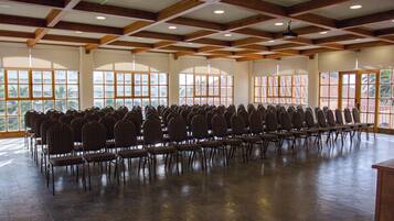 A large hall with rows of chairs and large windows.