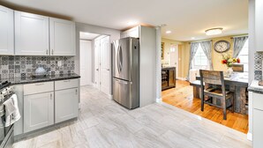 Eine moderne Küche mit weißen Schränken, einem Edelstahlkühlschrank und einem Essbereich mit Holztisch und Stühlen.