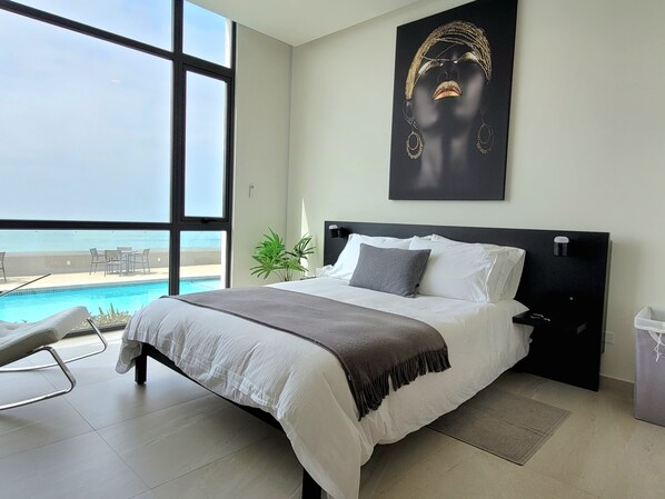 A modern bedroom with a large bed, a view of a swimming pool, and a large window. - Luxury Beachfront Condo in Rosarito with Pool & Jacuzzi (Playas de Rosarito)