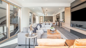 Un salon moderne avec un canapé, une table basse et un téléviseur. Un escalier mène à un niveau supérieur.