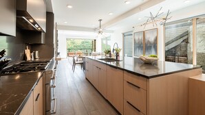 Une cuisine moderne dotée d’un grand îlot central, d’appareils électroménagers en acier inoxydable et d’armoires en bois.