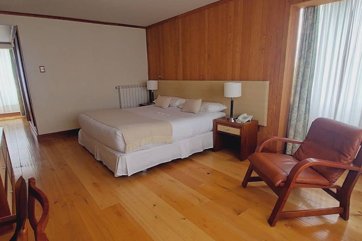 Ein Hotelzimmer mit Bett, Stuhl, Schreibtisch und Spiegel.