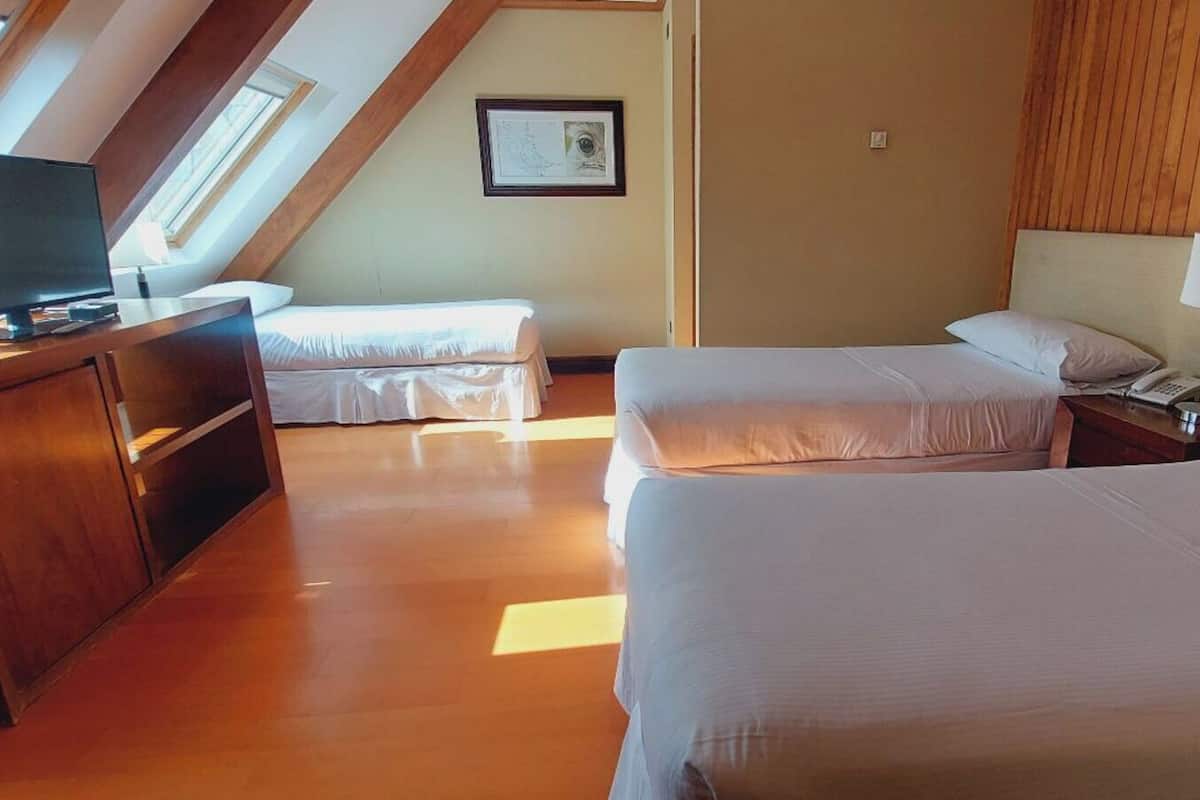 Ein Hotelzimmer mit zwei Betten, einem Schreibtisch mit Computer und einem Fenster mit Blick.