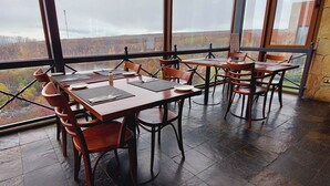 A restaurant with multiple tables and chairs, large windows offering a view of the countryside. - Hotel y Cabañas Llanuras de Diana- Caja Los Andes (Natales)