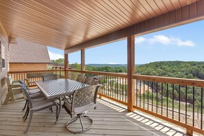 Eine Holzterrasse mit Tisch und Stühlen mit Blick auf eine bewaldete Landschaft.