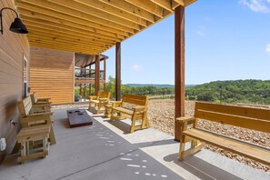 A covered outdoor seating area with wooden benches and a table, overlooking a scenic landscape.