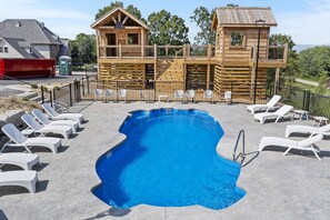 Eine Holzhütte mit Pool und Liegestühlen.