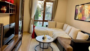 Un soggiorno moderno con un divano, una TV, un tavolino da caffè e un quadro appeso al muro.