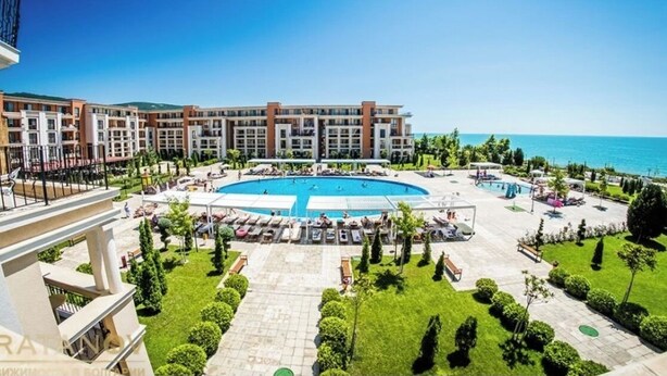 Un hotel con una grande piscina, diversi edifici e vista sul mare.