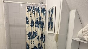 Een badkamer met een douche, wastafel, toilet en handdoekhouder.
