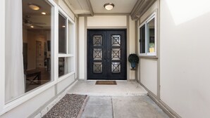 A hallway with a black double door, a potted plant, and a doormat. - WindnSea Beach Perfection - Walk to Beach, Pet Friendly & Parking! (La Jolla)