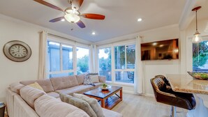 A spacious living room with a large sofa, a coffee table, and a dining area with a bar stool. - WindnSea Beach Perfection - Walk to Beach, Pet Friendly & Parking! (La Jolla)