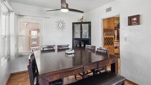 A large dining table with six chairs, a ceiling fan, and a decorative wall piece. - Palmera Place Uptown Phoenix (Phoenix)