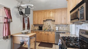 A kitchen with wooden cabinets, a stainless steel stove, a microwave, and a sink. - Palmera Place Uptown Phoenix (Phoenix)