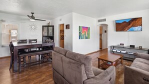 A spacious living area with a dining table, sofas, and a flat-screen TV. - Palmera Place Uptown Phoenix (Phoenix)