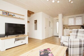 Un soggiorno moderno con una TV a schermo piatto, un mobile TV bianco e un divano a quadri.