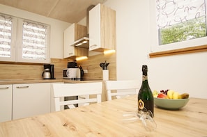A modern kitchen with white cabinets, a wooden countertop, a coffee maker, a microwave, and a bottle of champagne on a table. - Ferienhaus Liva - Das Ferienhaus Liva in Dranske auf Rügen (Dranske)