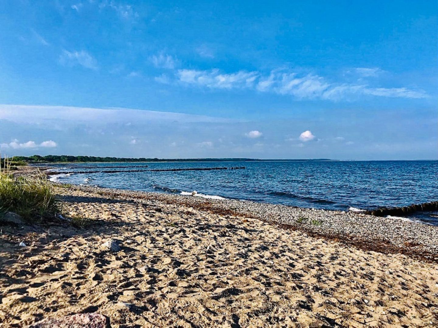 A beach with a pebbly shore and calm water.