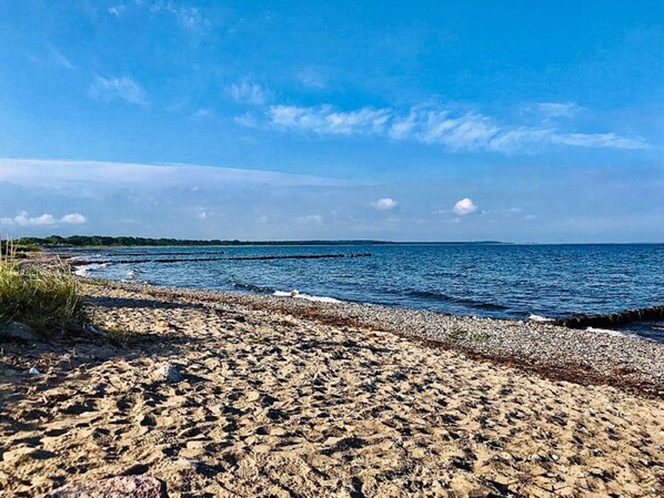 Una playa con orilla pedregosa y agua tranquila.