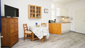 Eine kompakte Küche mit Essbereich, Holzschränken, einem Fernseher und einer kleinen Kücheninsel mit Kaffeemaschine.