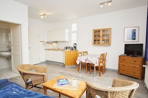 A compact living space with a kitchenette, dining area, and a TV. - Die Ferienwohnung Nr. 02 im Haus Rugier in Göhren - Haus Rugier (Göhren)