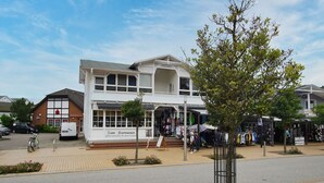 Un edificio a due piani con facciata bianca e un negozio al piano terra.