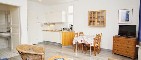 A compact living space with a kitchenette, dining area, and a TV.