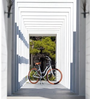 Ein Fahrrad, das in einer weißen, tunnelartigen Struktur mit geometrischer Form abgestellt ist.